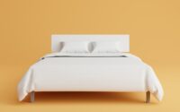 a bed with a white cover and pillows on top of it
